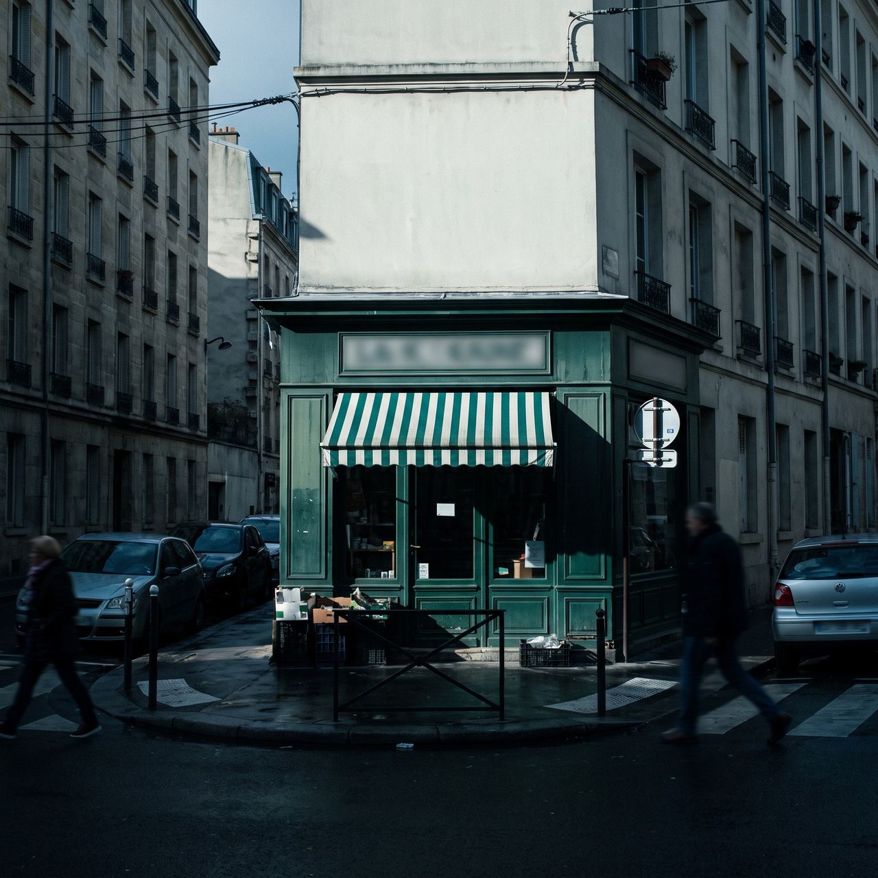 Devanture verte d’une petite boutique à l’angle d’une rue, passants.
